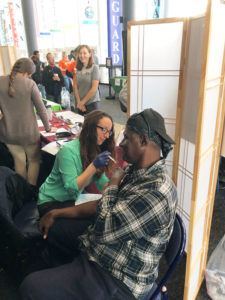 Pharmacist Joy Snyder administering influenza vaccine to one of the attendees during “Day of Services” at Project Homeless Connect.